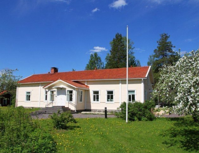 Pappila Vaalea hirsirakennus omenapuutarhan keskellä
